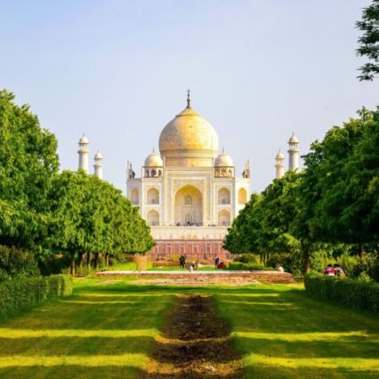 Stunning view of the Taj Mahal surrounded by lush greenery on a bright summer day.
